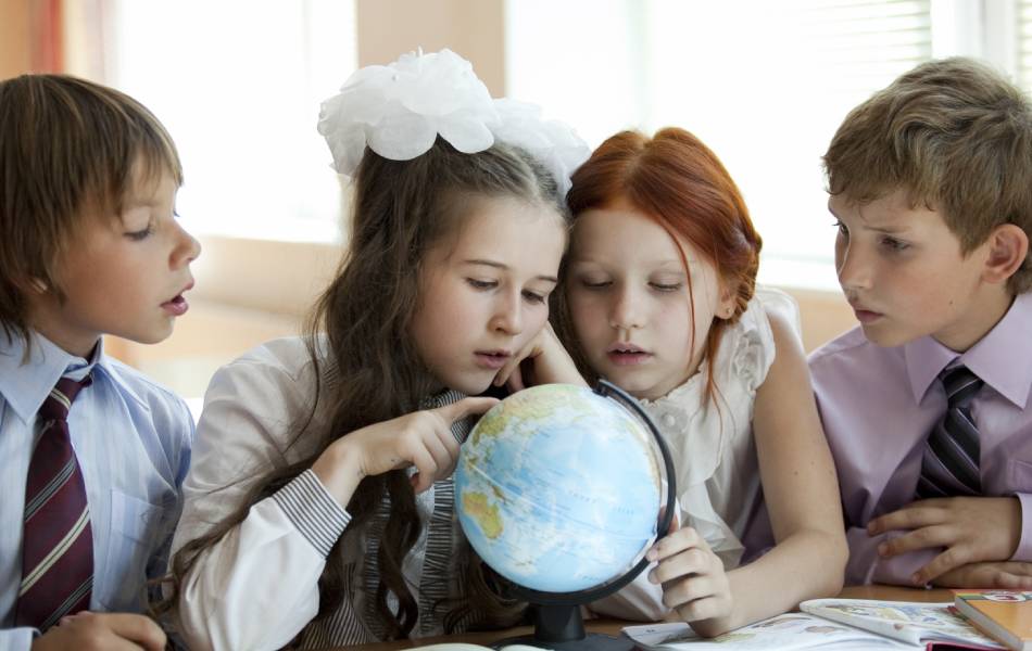Crianças durante a aula de geografia observando um globo terrestre
