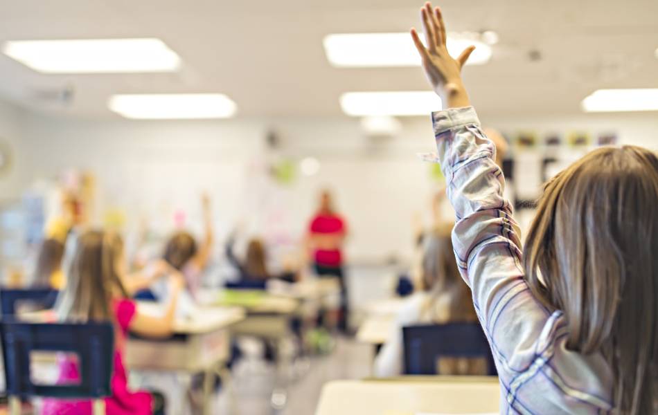 foto de aluna levantando a mão expressando dúvida durante uma aula em uma escola internacional