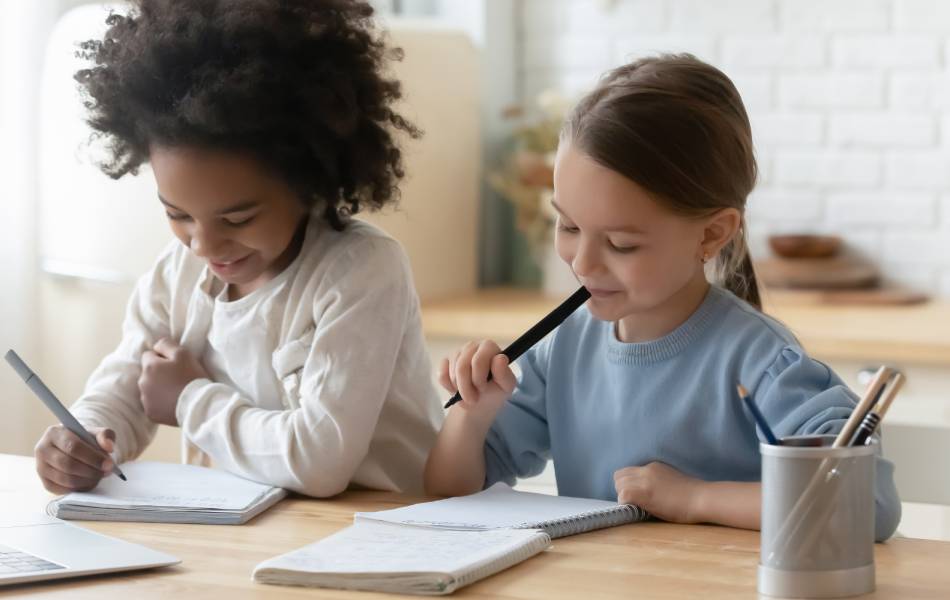 Duas meninas sentadas na cadeira fazendo autoavaliação em uma mesa