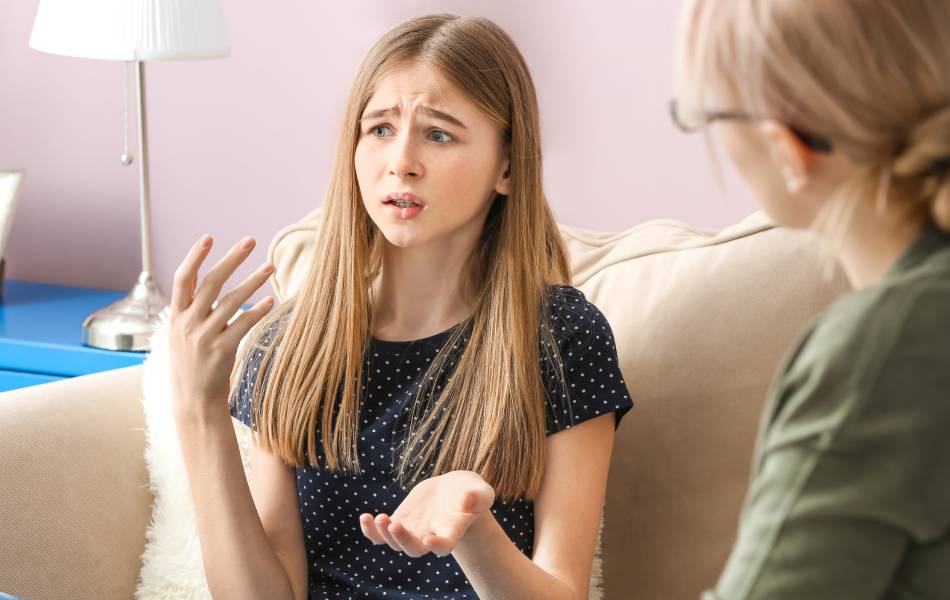 Mãe conversando com sua filha no sofá de casa