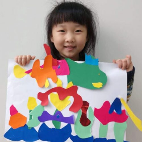 Criança exibindo trabalho artesanal colorido