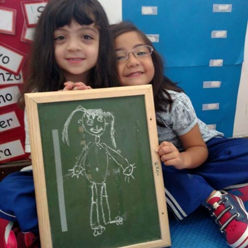 Duas crianças segurando pequeno quadro negro com ilustração