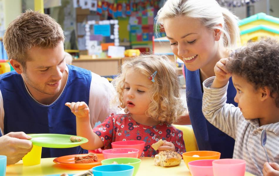 Professores ajudando os jovens alunos a alimentar-se durante a aula