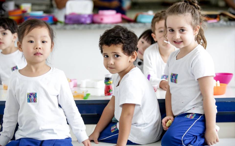 Crianças juntas socializando dentro da sala de aula de uma escola internacional