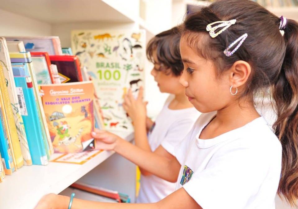 Crianças lendo livro dentro da sala de aula